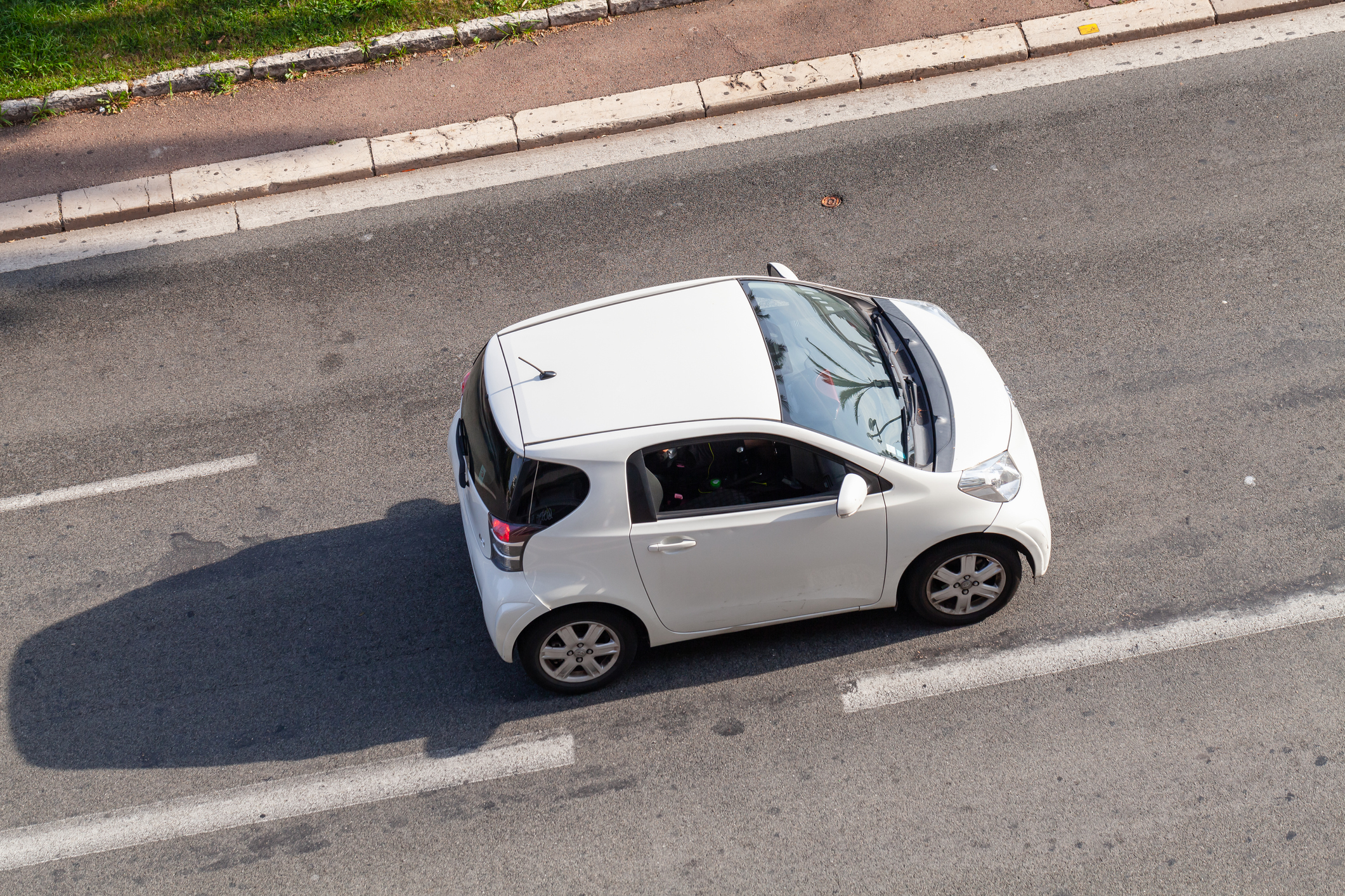 White Toyota iQ is on the road at sunny day, top view